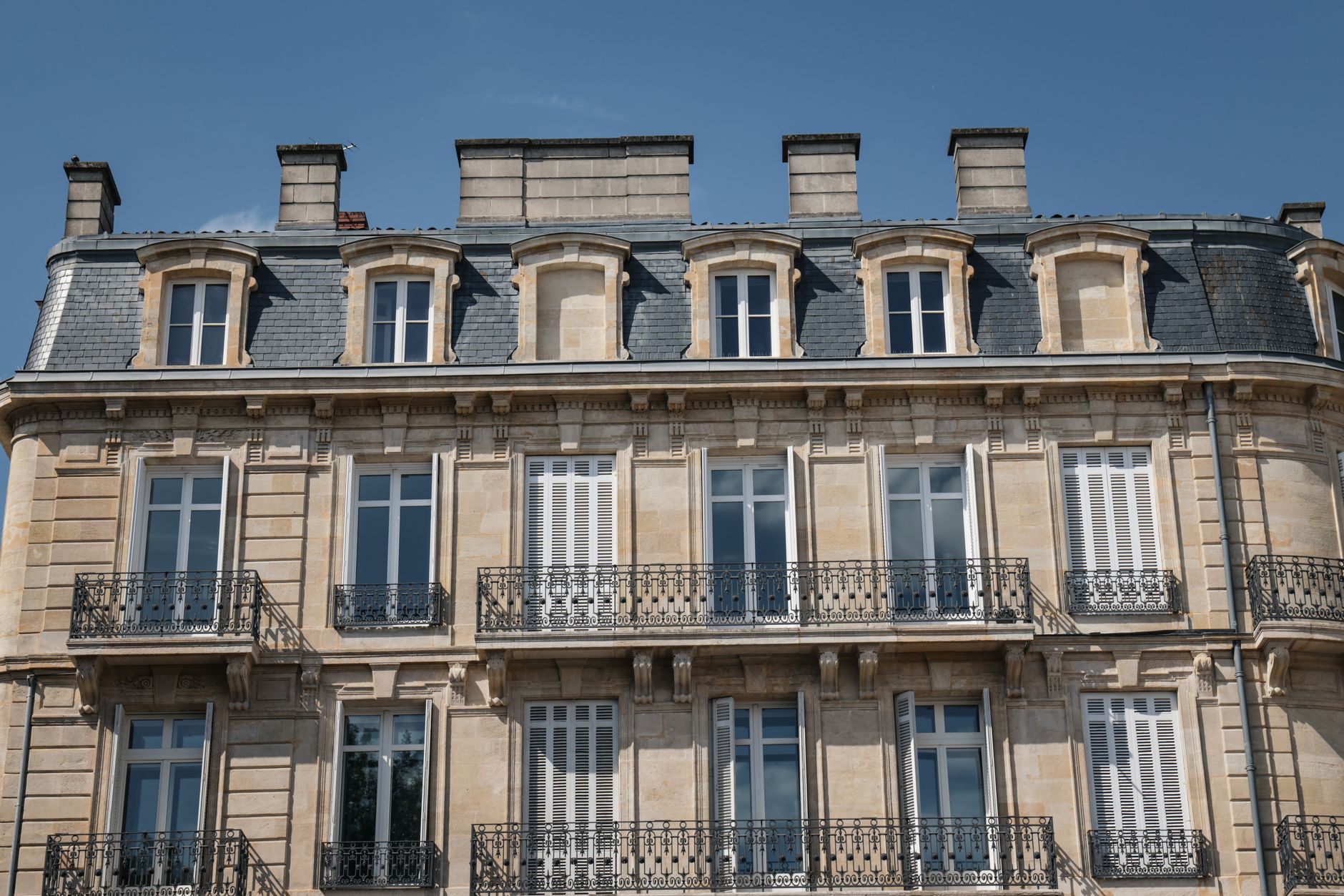 Façade d'immeuble bordelais en pierre de taille calcaire, avec balcons en ferronnerie et toiture en ardoise