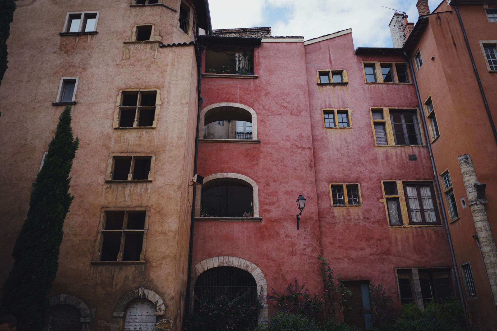 Façades d'immeubles anciens du Vieux Lyon, enduits ocre et rose, fenêtres à meneaux et galeries à arcades