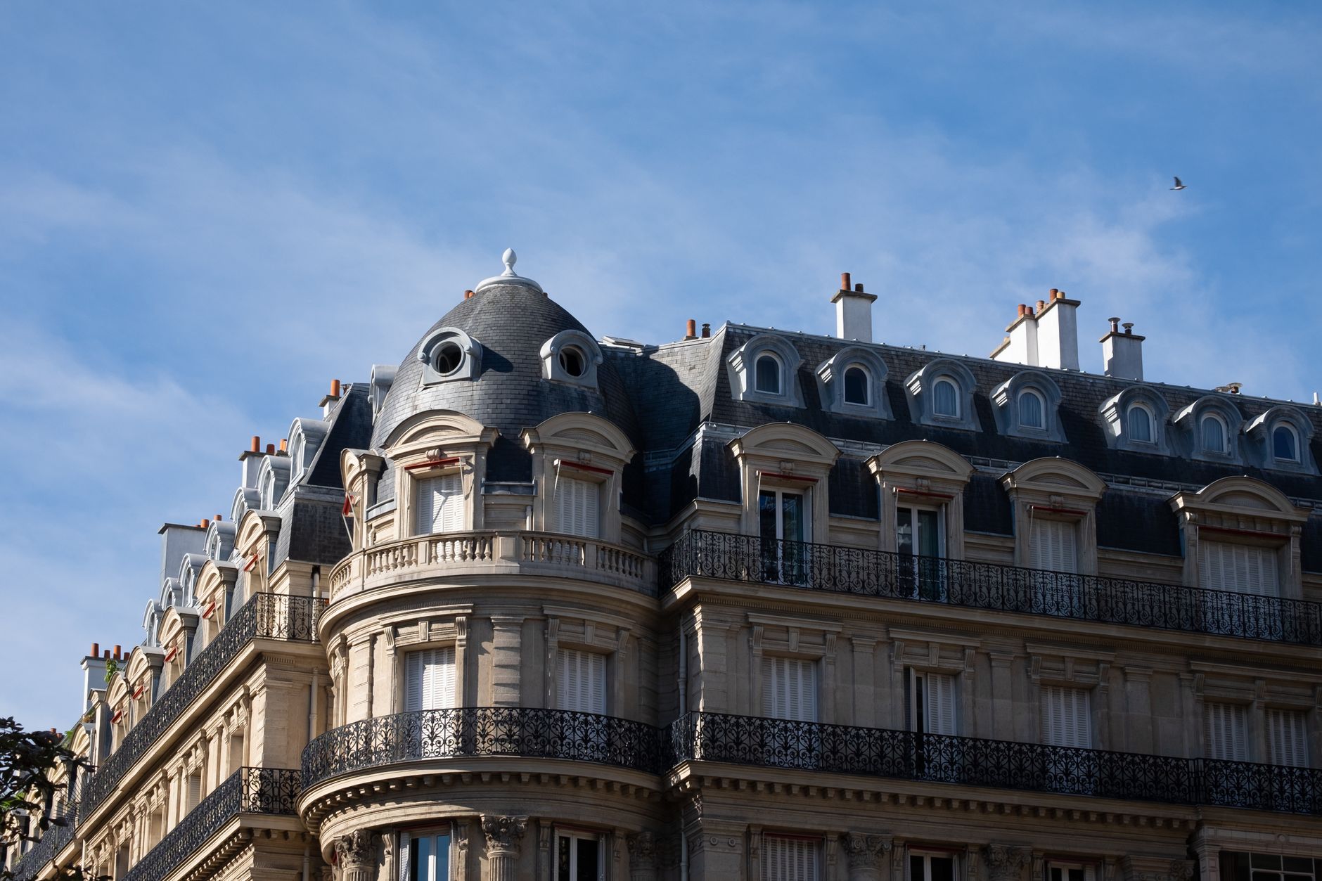 Immeuble parisien à façade en pierre ornée et toit mansardé en zinc
